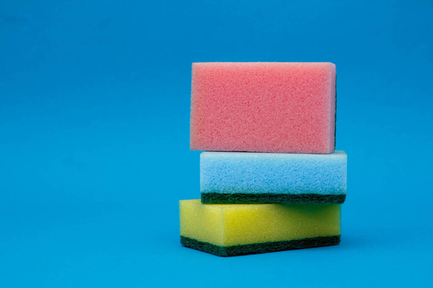 Multicolored sponges for cleaning and washing dishes on a blue background. Space for text. - Foto, afbeelding
