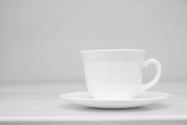White ceramic cup with saucers on white table. Space for text. - Fotó, kép
