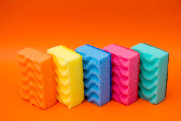 Multicolored sponges for cleaning and washing dishes on a orange background. Space for text. - Photo, Image