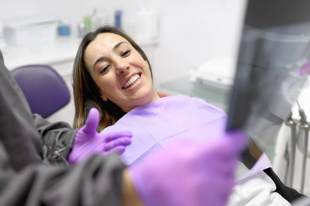 Naishammaslääkäri osoittaa potilaita röntgenkuva hammaslääkärin toimistossa. - Valokuva, kuva