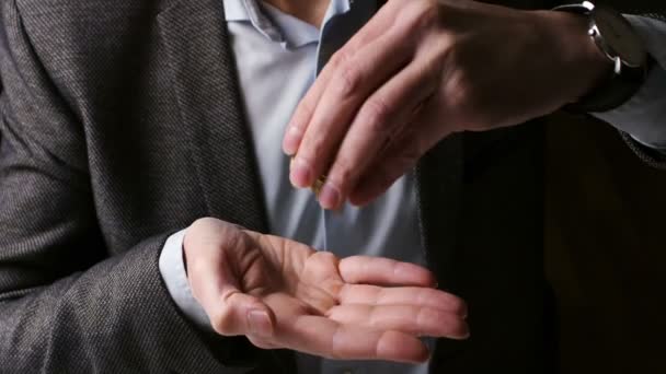 Um comerciante joga moedas amarelas bitcoin na palma da mão esquerda. O proprietário de um grande número de bitcoins. - Filmagem, Vídeo
