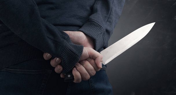 Close-up on the murderer holding the murder weapon. Man with a knife in his hand - Foto, afbeelding