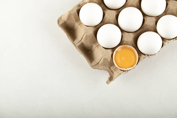 Nyers tyúktojás tojásos dobozban, fehér alapon - Fotó, kép