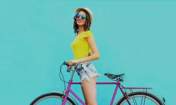 Happy young smiling woman with bicycle on a blue background - Foto, Imagen