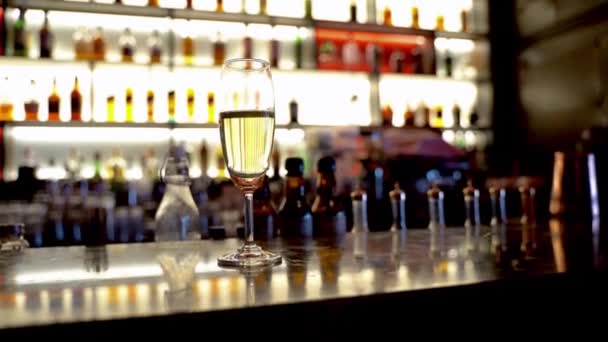 bicchiere di vino sul tavolo del bancone con mensola del cocktail bar sullo sfondo. - Filmati, video