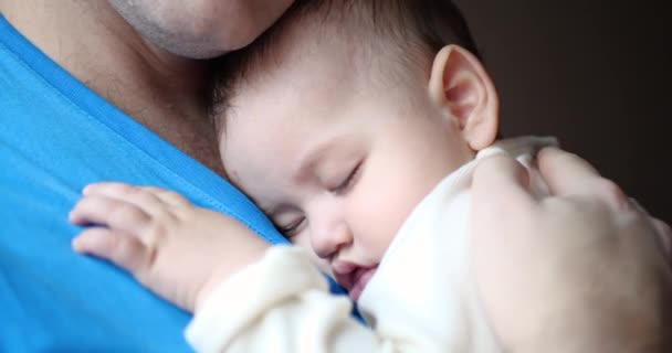 小さな子供が父親の腕の中で眠ってしまいました。パパは赤ん坊を寝かしつけてた。接近中だ。4k - 映像、動画