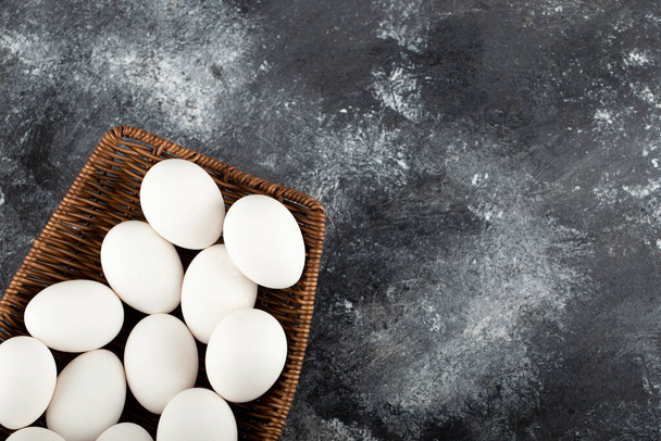Un vimini di legno pieno di uova di pollo crude bianche - Foto, immagini