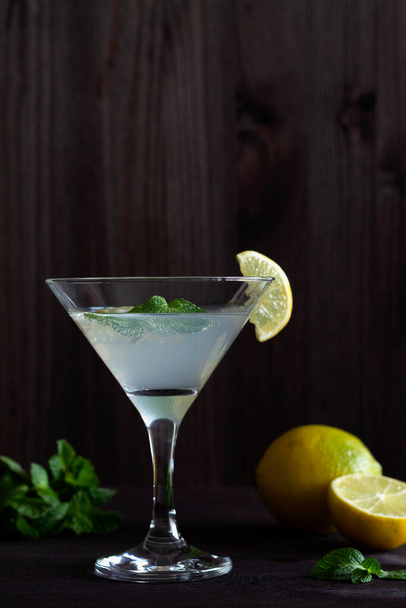 Margarita cocktail baarissa. martini lasi cocktail oliiveja ja sitruuna vihreä minttu puinen tausta. Lasit martinille mustalla pöydällä. Kopioi alkoholijuomat. pystysuora - Valokuva, kuva
