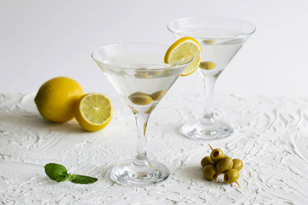 bevande alcoliche. cocktail margarita al bar. due bicchieri da martini di cocktail con menta verde e olive su fondo bianco. Bicchieri per martini con olive in tavola. copia spazio. - Foto, immagini