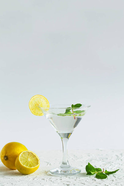 алкогольні напої. Коктейль з маргаритою у барі. Мартіні склянка коктейлю з зеленою м'ятою та оливками на білому тлі. Окуляри для мартіні з лимоном на столі. копіювання простору. вертикальний
 - Фото, зображення