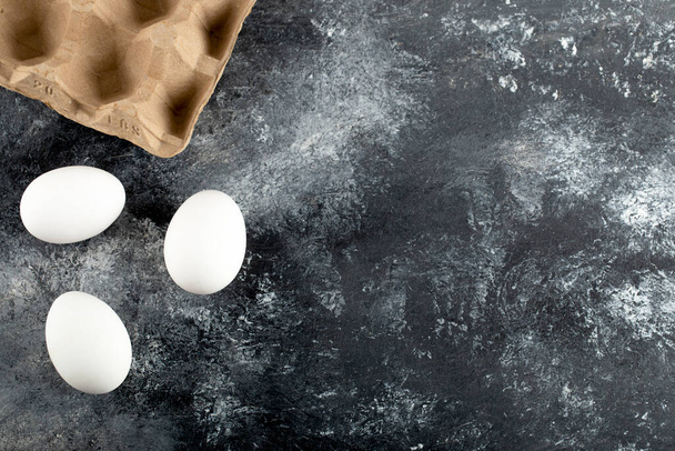 Mermer bir arka planda üç çiğ tavuk taze yumurta. - Fotoğraf, Görsel