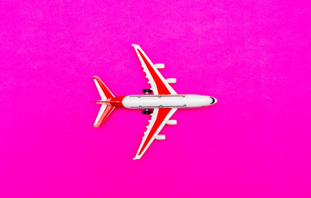 Avion modèle passager blanc et rouge sur fond rouge et rose. Espace libre pour le texte. Concept de voyage. - Photo, image