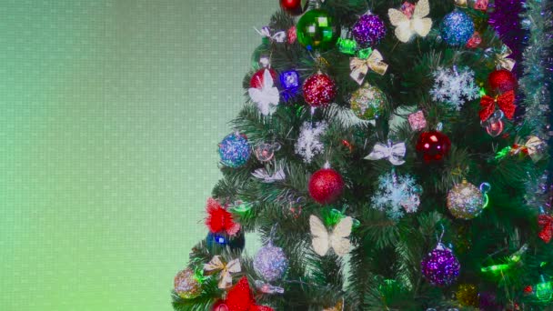 Weihnachtsbaum geschmückt mit verschiedenen bunten Spielzeugen auf grünem Hintergrund - Filmmaterial, Video