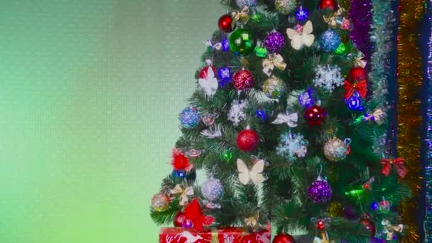 Geschmückter Weihnachtsbaum mit Geschenken und Neujahrsschmuck auf grünem Hintergrund - Filmmaterial, Video