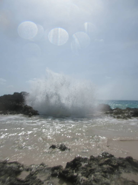 Krachtige golf raakt rotsen door het creëren van spray - Foto, afbeelding