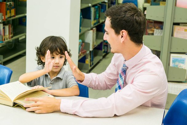 hombre profesor y niño estudiante aprender con libro en librería fondo - Foto, imagen