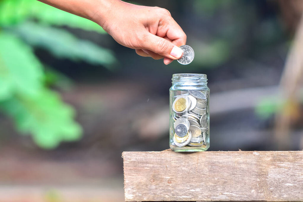 Рука положить деньги монеты на открытом воздухе - Фото, изображение