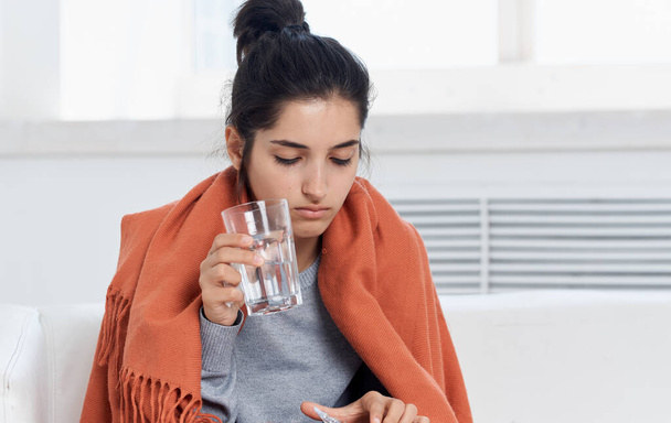 Allergic woman in an orange plaid sweater glass of water pills health problems - Фото, зображення