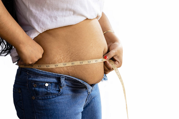 środkowa część boczna widok z indyjskiej kobiety pomiaru tłuszczu brzuch z taśmą na białym tle - Zdjęcie, obraz