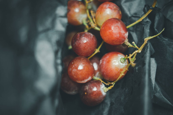 Fresh of bright red grapes on black paper. Selective focus - 写真・画像