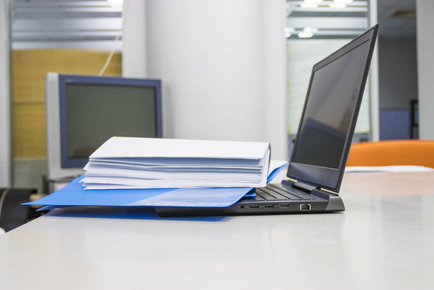 Μπλε φάκελο έγγραφο με έγγραφα και φορητό υπολογιστή σε λευκό τραπέζι στην αίθουσα συνεδριάσεων  - Φωτογραφία, εικόνα