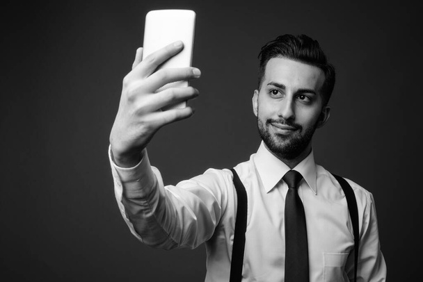 Studio shot of young handsome bearded Iranian businessman against brown background - 写真・画像