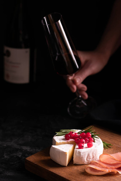 Camembert cheese and glass of wine in hand - Fotoğraf, Görsel