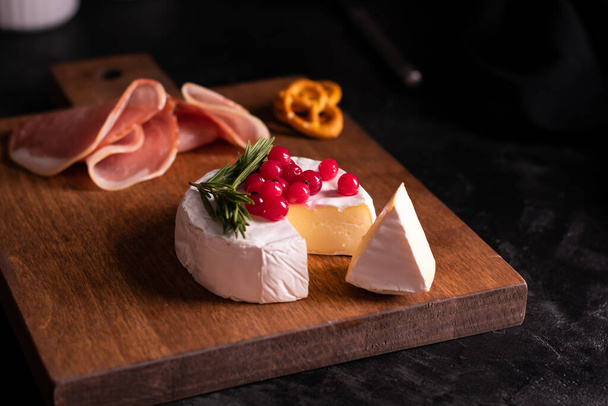 Camembert cheese decorated with berries and rosemary - 写真・画像