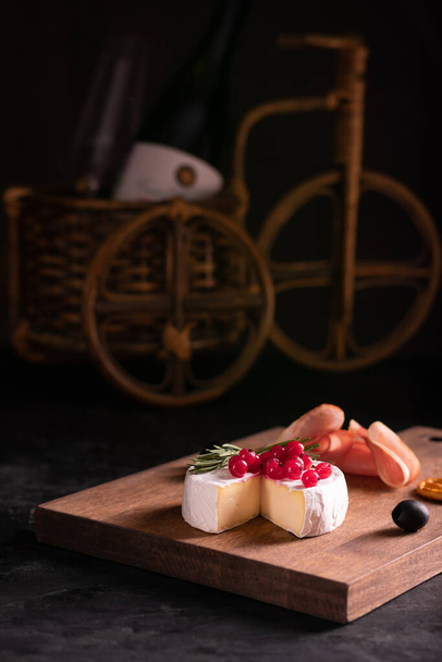 Camembert cheese decorated with red currant on a wooden board and red wine - Fotografie, Obrázek