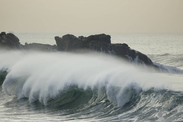 Розбиття хвилі вітряним бризком на заході сонця. Північне португальське скелясте узбережжя
. - Фото, зображення