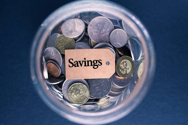 Saving Concept: Etiqueta de ahorro con monedas en el cristal - Foto, Imagen
