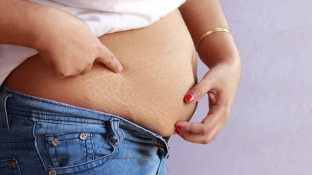 zijaanzicht van striae na de zwangerschap op dikke buik van een indische vrouw in jeans op witte achtergrond - Video