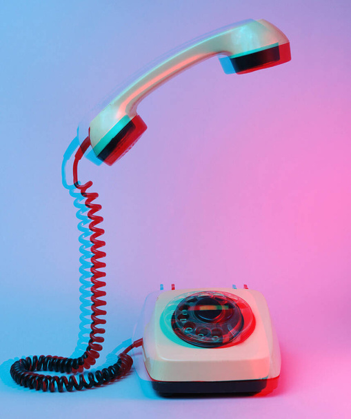 Efekt usterki Stary telefon obrotowy z szybkim uchwytem telefonu, niebieskie czerwone światło neonowe, lata 80. - Zdjęcie, obraz