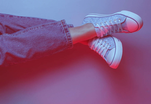 Konsept gevşedi. Kot pantolonlu ve spor ayakkabılı kadın bacakları. Duotone etkisi - Fotoğraf, Görsel