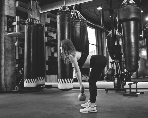Functional training. Woman doing deadlift exercise with kettlebell indoors at gym - Foto, imagen