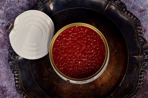 Nyissa ki a konzervdobozt vörös lazac kaviárral antik ezüst tányéron. Rusztikus háttér, felülnézet, másolás tér - Fotó, kép