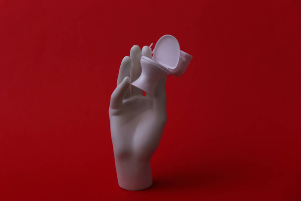 Manequim branco mão segurando mini banheiro no fundo vermelho - Foto, Imagem