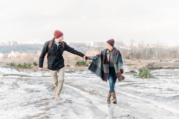 Cool valentine. Happy loving couple walking in snowy winter field, spending Christmas vacation together. Outdoor seasonal activities. Lifestyle capture. - 写真・画像