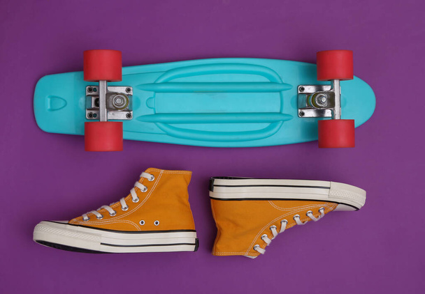 Cruiser board and gumshoes on purple background. Youth concept. Top view - Foto, afbeelding