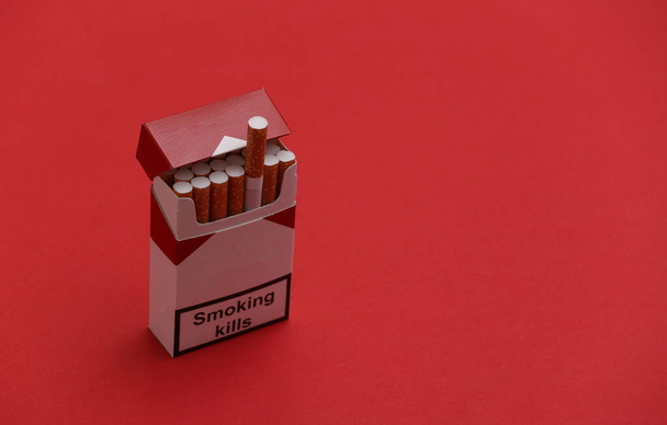 Envase de cigarrillos sobre fondo rojo. Fumar mata. - Foto, imagen