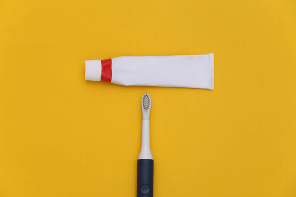 Zahnpflege. Tube Zahnpasta mit Zahnbürste auf gelbem Hintergrund. Ansicht von oben - Foto, Bild