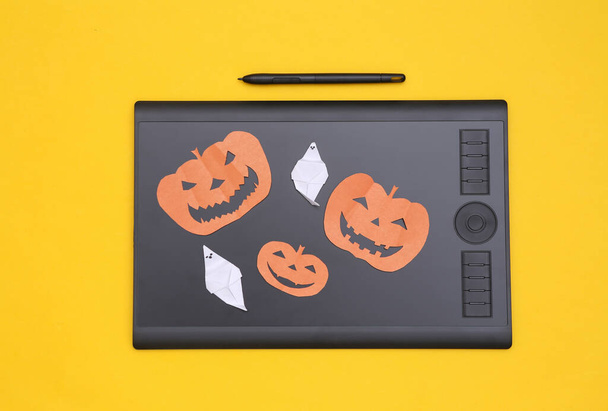 Graphics tablet, spook en Halloween pompoen op gele achtergrond. Bovenaanzicht - Foto, afbeelding