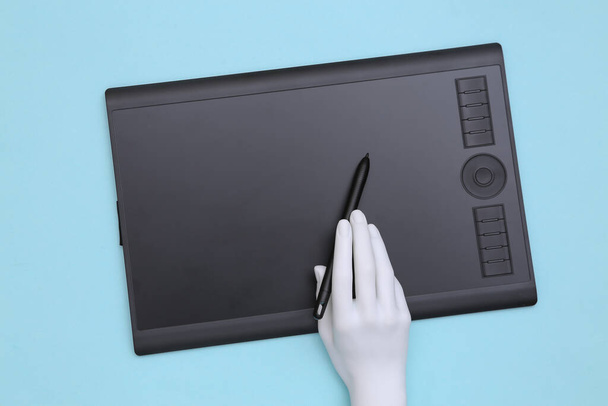 La mano de Menequin trabaja en una tableta gráfica. Fondo azul - Foto, Imagen