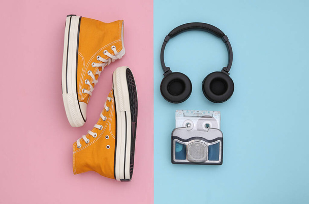 Retro sneakers και mini audio player με στερεοφωνικά ακουστικά σε μπλε ροζ φόντο. Άνω όψη - Φωτογραφία, εικόνα