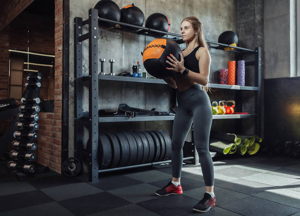 Modelo de fitness femenino joven haciendo ejercicio con balón de medicina en el gimnasio. Caucásico mujer haciendo crossfit entrenamiento. - Foto, Imagen