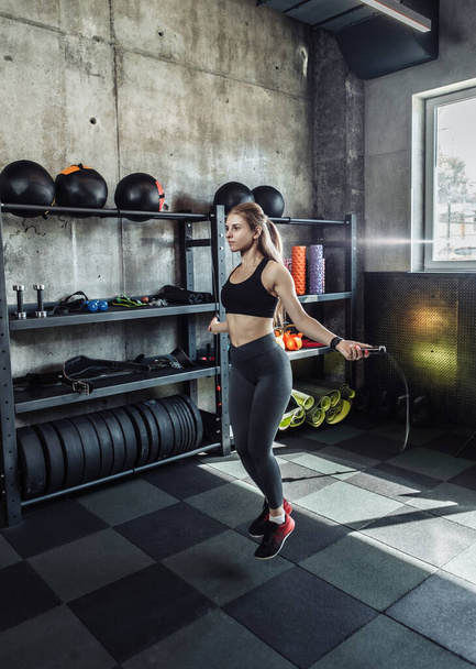 Attractive athletic woman jumping rope in gym - Photo, Image