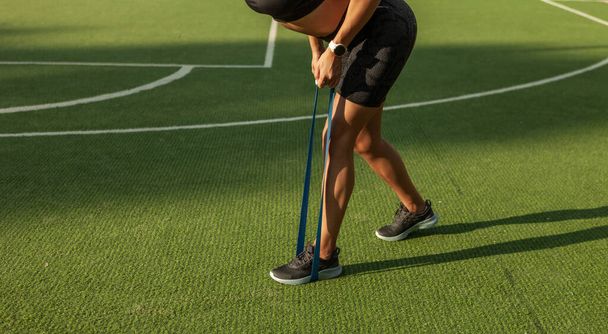 Jóvenes ejercicios de mujer delgada con bandas de goma de fitness al aire libre - Foto, Imagen
