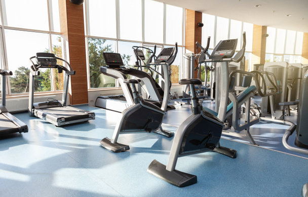 Interior de uma moderna sala de fitness ginásio com grandes janelas. Esteiras e bicicletas de exercício - Foto, Imagem