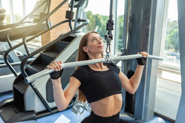 Schöne junge, fitte Frau trainiert auf einem Latexgerät im Fitnessstudio - Foto, Bild