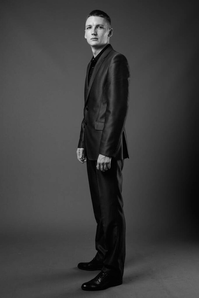 Studio shot of young businessman wearing suit against brown background - Fotoğraf, Görsel